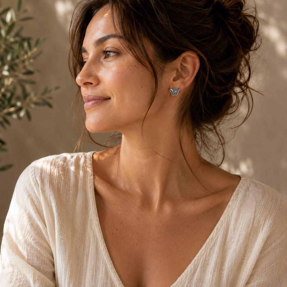 Woman wearing abalone butterfly silver stud earrings with a soft ivory top.