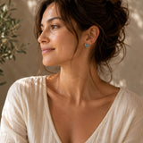 Woman wearing abalone butterfly silver stud earrings with a soft ivory top.
