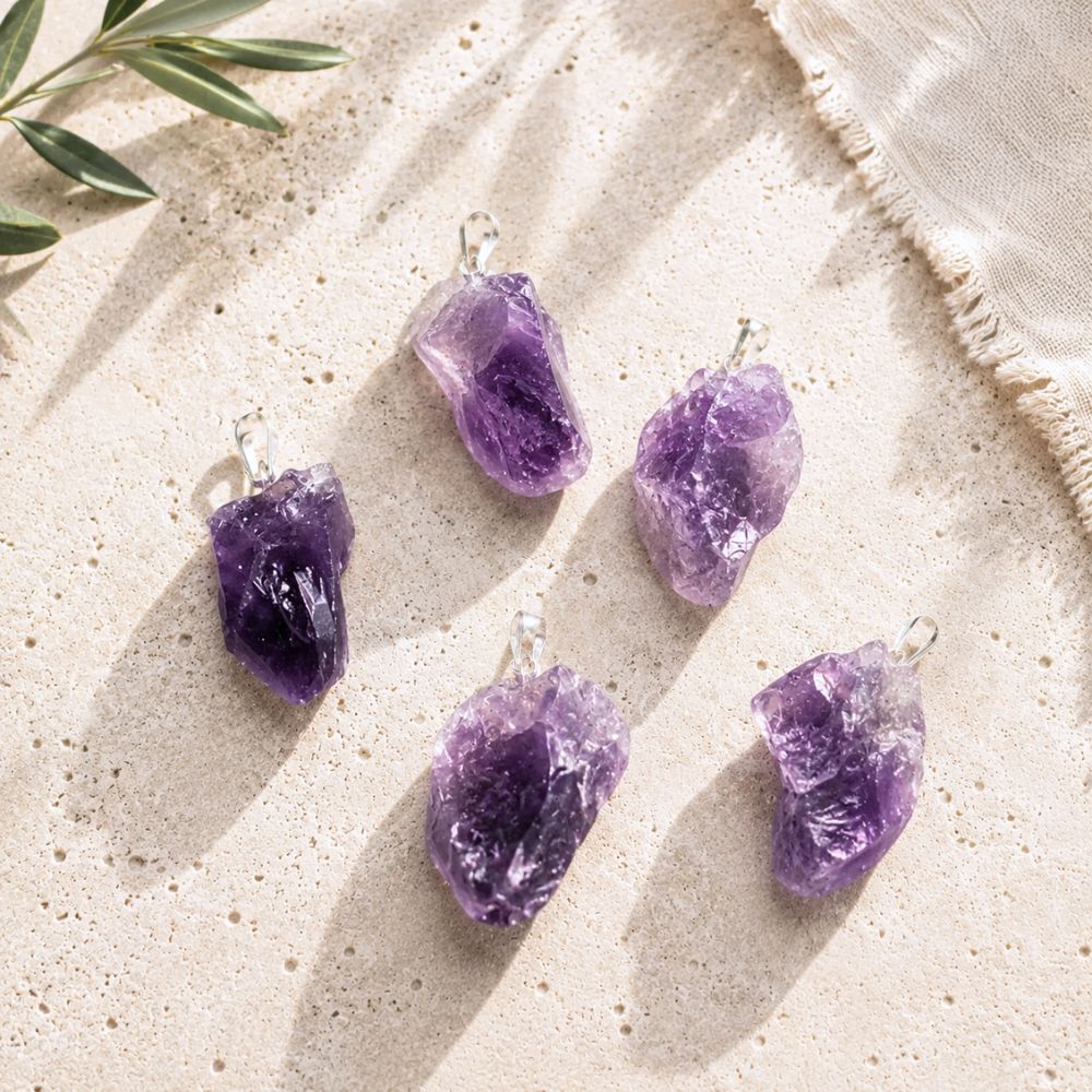 Aura Amethyst Raw Pendant assortment displayed on natural stone surface