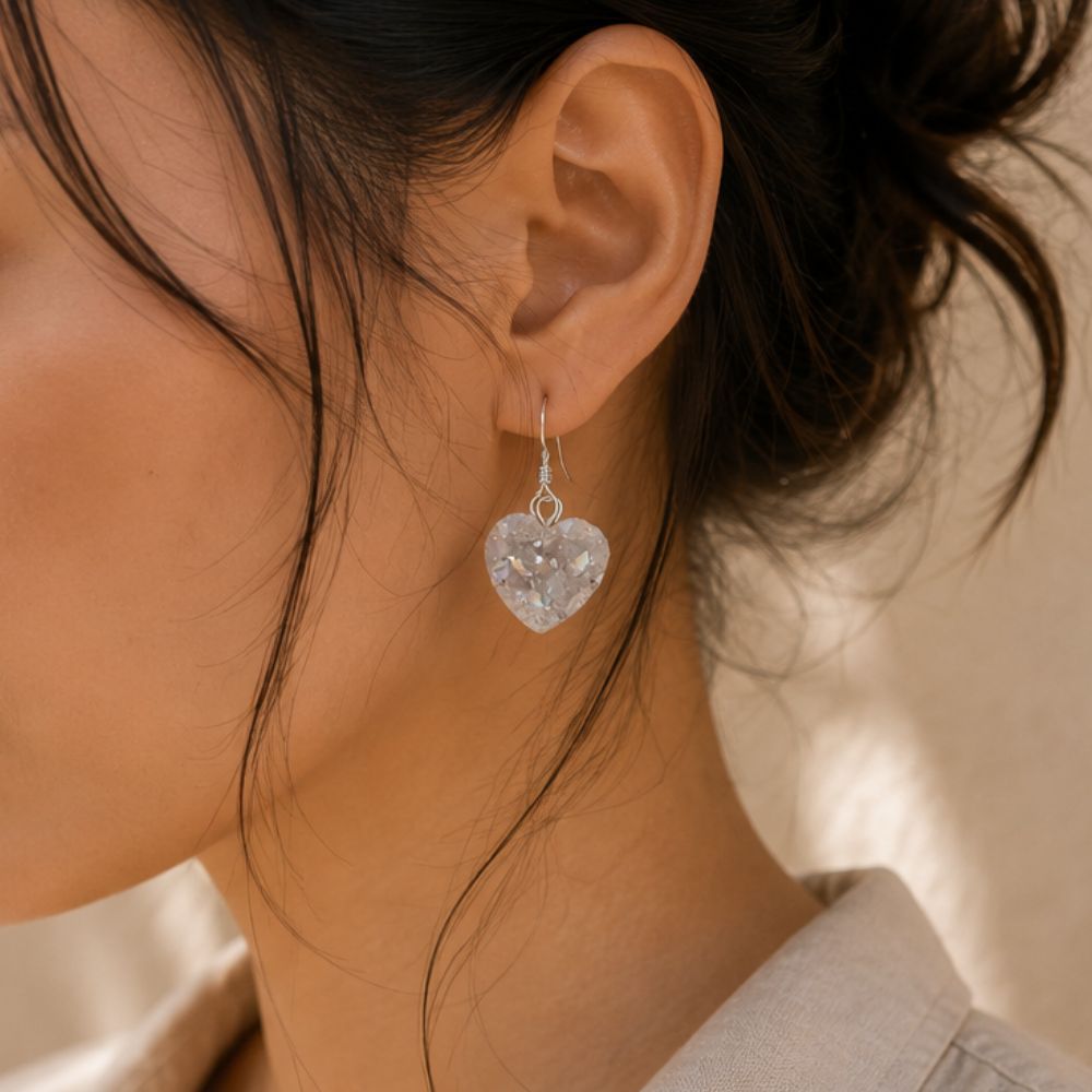 Close-up of a person wearing a sparkling heart-shaped earring with a blurred background