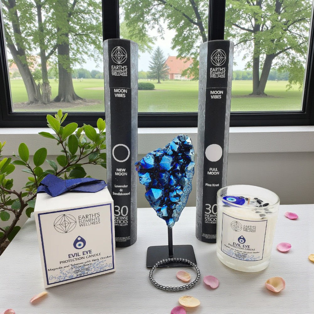 Candle and packaging with decorative elements on a table by a window with a view of trees.