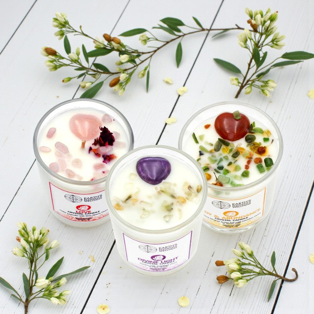 Three crystal candles on a white wooden surface with floral decorations.