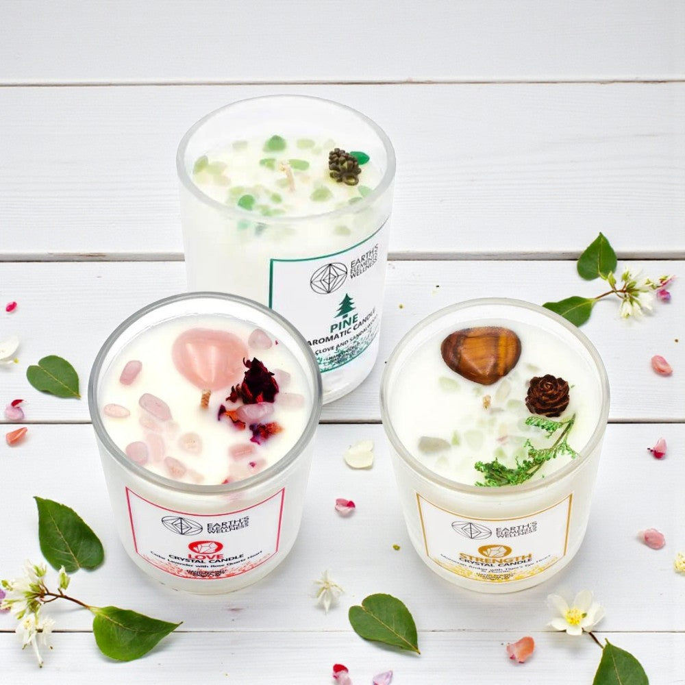 Three scented candles with decorative elements on a white wooden surface with flowers and leaves.