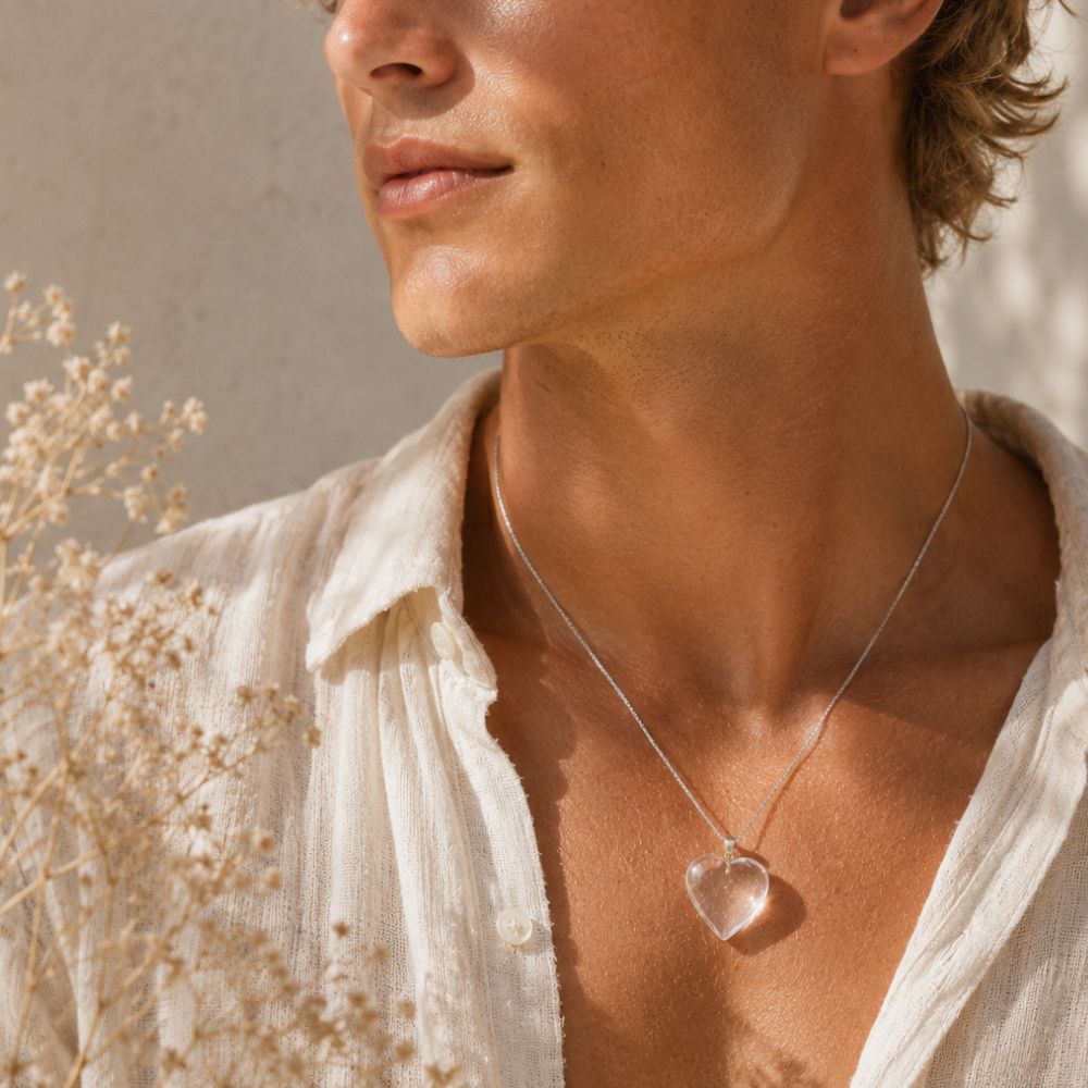 Person wearing a necklace with a heart-shaped pendant in a natural setting
