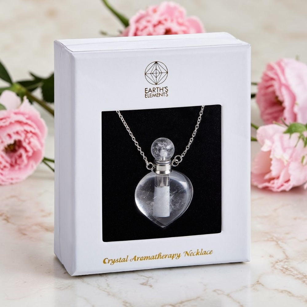 Crystal aromatherapy necklace in a white box with pink flowers in the background