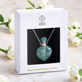 Crystal aromatherapy necklace in a white box with 'Earth's Elements' branding, surrounded by white flowers.