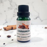 Bottle of cinnamon essential oil with cinnamon sticks on a marble background