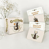 Gratitude card set with cards and packaging on a light surface with flowers in the background