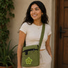 Woman holding a green crossbody bag with a flower design, standing in front of a wooden door.