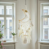 Decorative dreamcatcher hanging in a room with windows and a radiator.