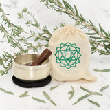 Heart Chakra Singing Bowl in Pouch on a white background with rosemary leaves.
