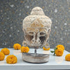 Decorative Buddha head sculpture with yellow flowers on a gray surface