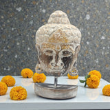 Decorative Buddha head sculpture with yellow flowers on a gray surface