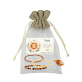 A jewelry gift set in a sheer white drawstring pouch with a beige fabric top and a printed card reading 'Sun.' The set includes three beaded bracelets inCitrine, Goldstone, Mookaite, plus a small citrine crystal, all on a plain white background.