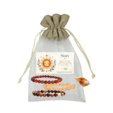 A sun-themed crystal bead bracelet gift set in a sheer white drawstring pouch with a beige fabric top. The set includes three beaded bracelets goldstone, citrine, and mookaite, and a printed card labeled 'Sun'.