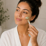 Woman using a facial roller on her face with a neutral background