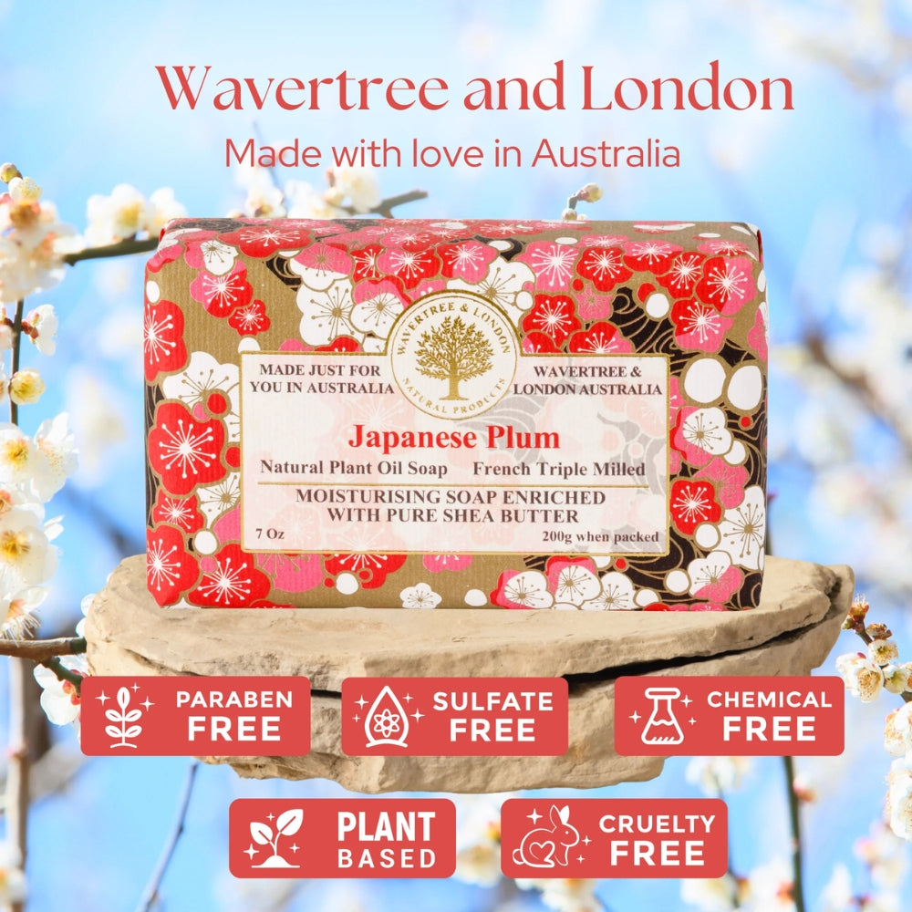 A boxed bar of soap from Wavertree and London, labeled Japanese Plum, displayed on a stone pedestal with a blurred blue sky and white blossoms background. Text at the top reads 'Wavertree and London Made with love in Australia,' and six red badges at the bottom say paraben free, sulfate free, chemical free, plant based, and cruelty free.