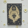 Earths Elements Goddess Journal on a light gray background with white flowers.