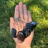 Hand holding a Black Obsidian Keychainagainst a grassy background