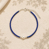 Blue beaded bracelet with a pearl on a beige fabric background