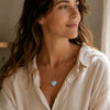Woman wearing a Larimar heart pendant with a sterling silver setting on a delicate silver chain.