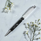 Pen with decorative elements on a light gray surface with white flowers