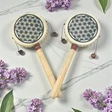 Two Hand Drum with floral designs on a marble surface with purple flowers.