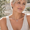 Delicate moonstone beaded necklace with a pear-shaped white moonstone pendant and sterling silver chain, worn with light-colored clothing in soft natural daylight.