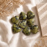 Olive Serpentine mini heart pendants displayed on a natural stone surface