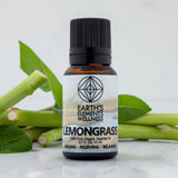 Bottle of Earth's Elements Wellness Lemongrass essential oil with lemongrass leaves in the background.