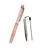 A pink patterned retractable pen shown disassembled with its cap removed, alongside a metal refill and a black-capped pen needle, on a plain white background.