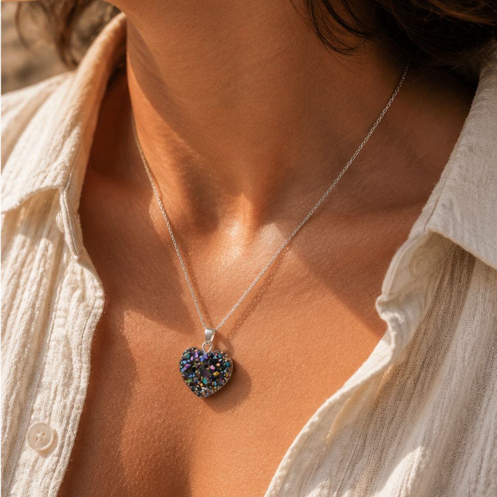 Necklace with a heart-shaped multicolored pendant worn by a person in a light-colored shirt.