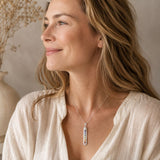 Person wearing a Chakra Selenite point pendant on a delicate silver chain with neutral clothing in warm natural light.