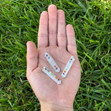 Three small crystal sticks with colorful stones held in a hand on grass