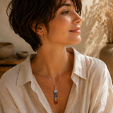 Person wearing a Chakra point pendant on a delicate silver chain with neutral clothing in warm natural light.