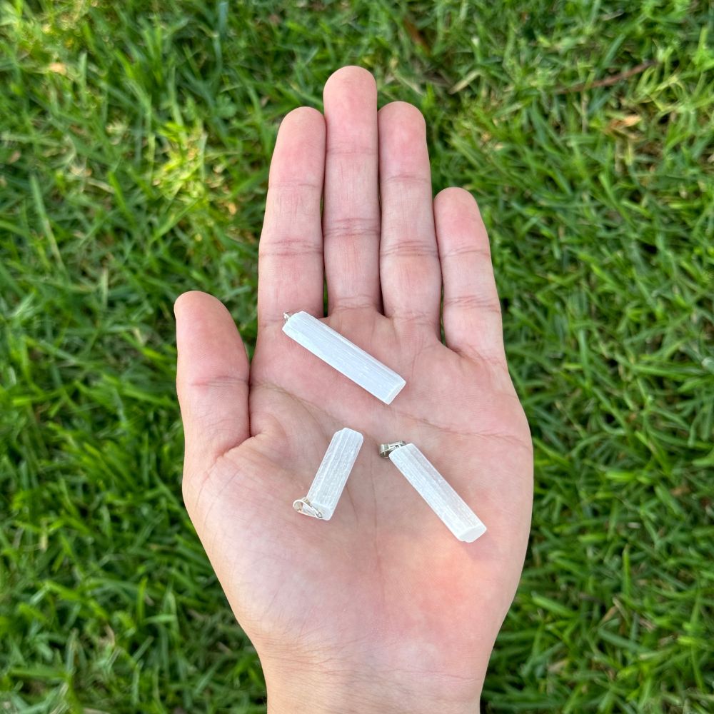 Hand holding threePoint Pendant - Selenite against a grass background