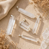 Person wearing a Clear Quartz point pendant on a delicate silver chain with neutral clothing in warm natural light.