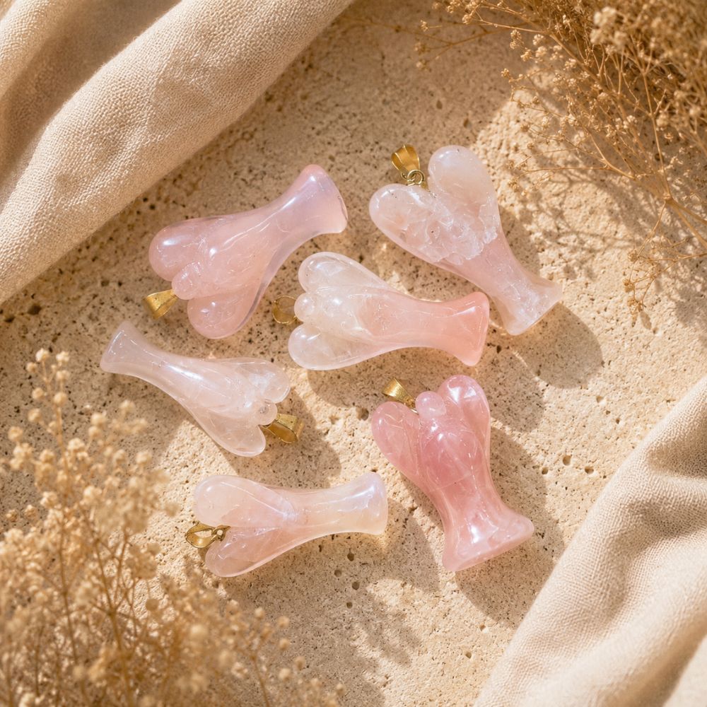 Rose Quartz Angel Pendants displayed on a neutral stone background with soft linen and dried botanicals.