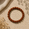 Brown beaded bracelet on a textured beige surface