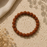 Brown beaded bracelet on a textured beige surface