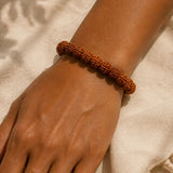 Brown beaded bracelet on a wrist with a neutral background