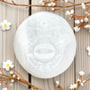 Selinite palmstone with geometric patterns on a wooden surface with floral elements