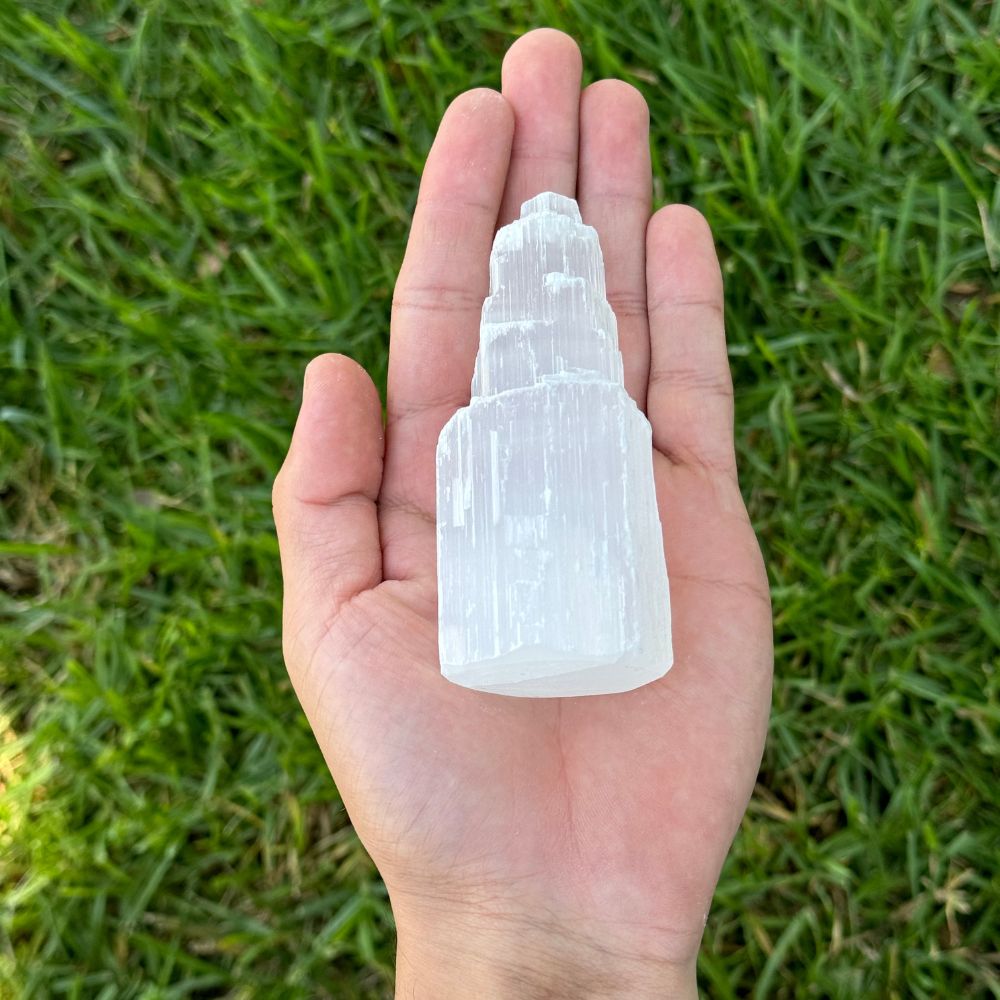 selenite twoer in hand above green grass