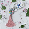 Keychain with tassel and colorful design on a marble surface with flowers and leaves.