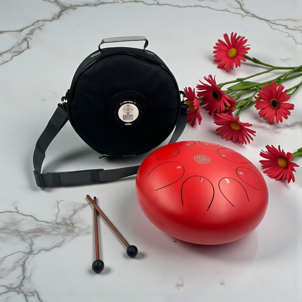 Red Steel Tongue Drum - 12" with carrying case, drumsticks, and red flowers on a marble surface