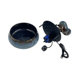 A small round ceramic bowl with a dark blue to gray glazed finish, shown next to a black electronic device with a USB cable on a plain white background.