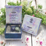 Crystal stone pack with packaging labeled 'Wisdom' on a wooden surface with plants in the background.