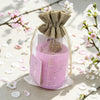 Pink candle in a decorative bag with cherry blossoms in the background