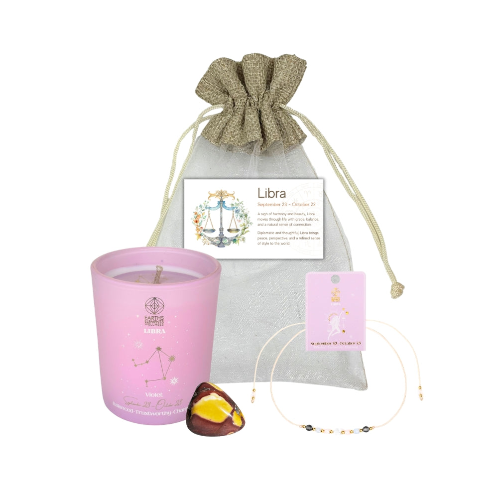 Pink candle with Libra zodiac card, drawstring bag, and decorative stones on a white background