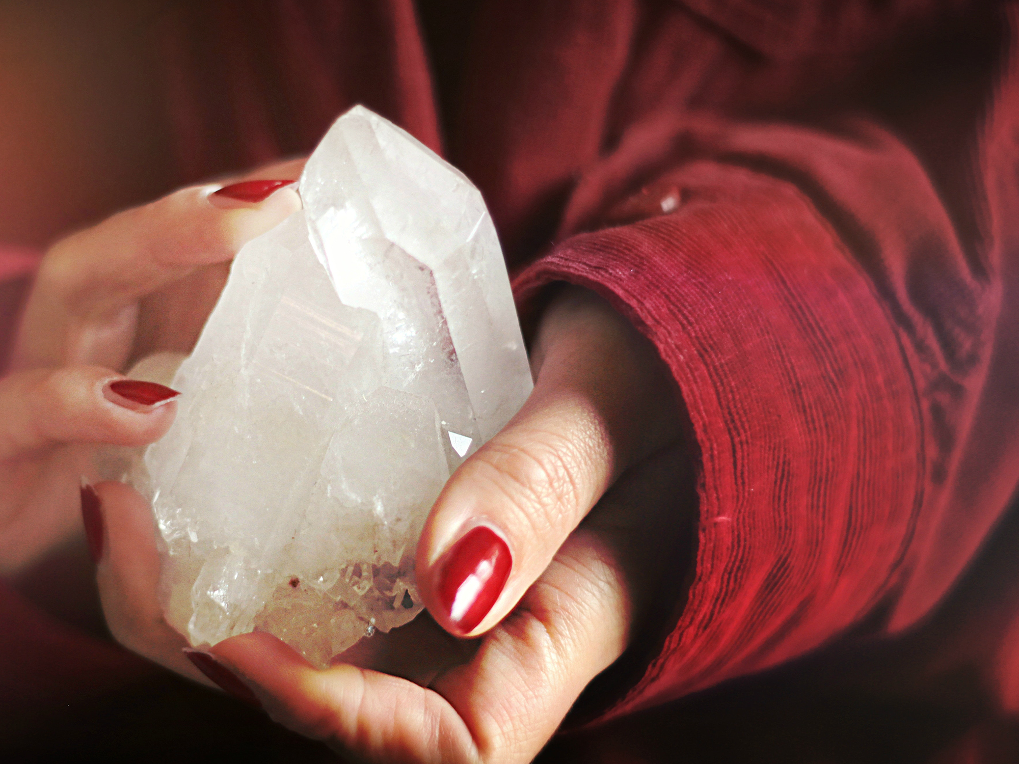 hands holding a large piece of clear quartz
